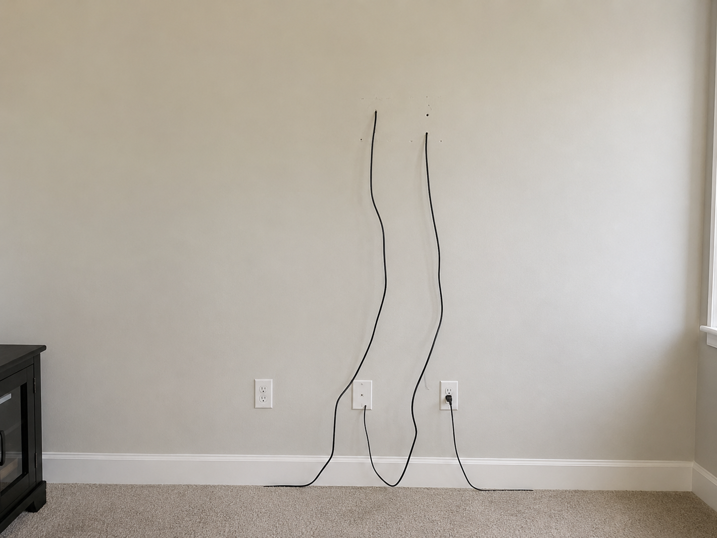 Living room wall before TV mounting with exposed cords hanging down in Lumberton